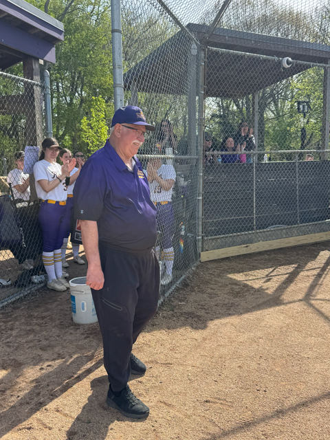 Coach Ron Niebauer smiling in front of a fence. 