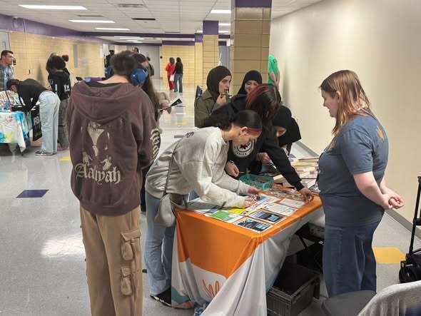 Students looking at items on a table in a hall. 