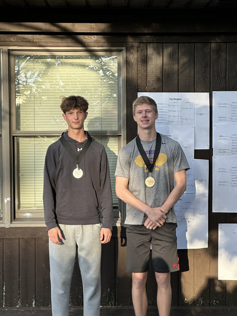 Two young men posing with medals around their necks. 