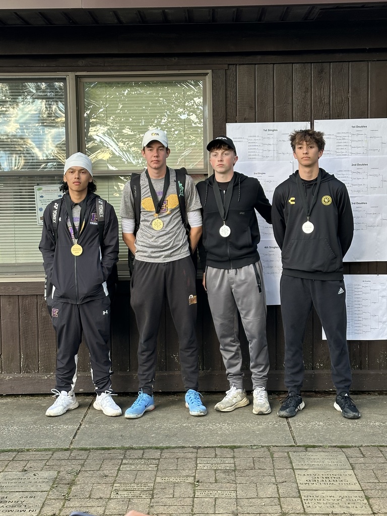 Four young men are posing with medals around their necks. 