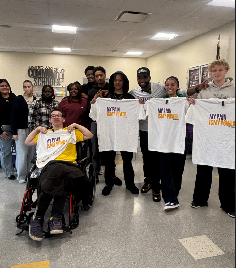 Erie High students with guest speaker David Powertalk holding up shirts from the assembly.