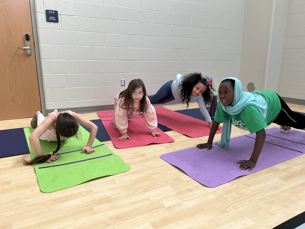 Students in gym class stretching on yoga mats.
