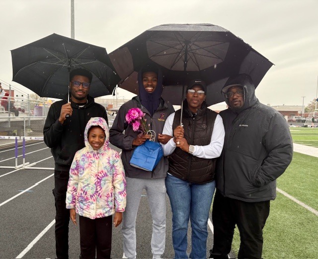 Family standing outside while they hold umbrellas. 