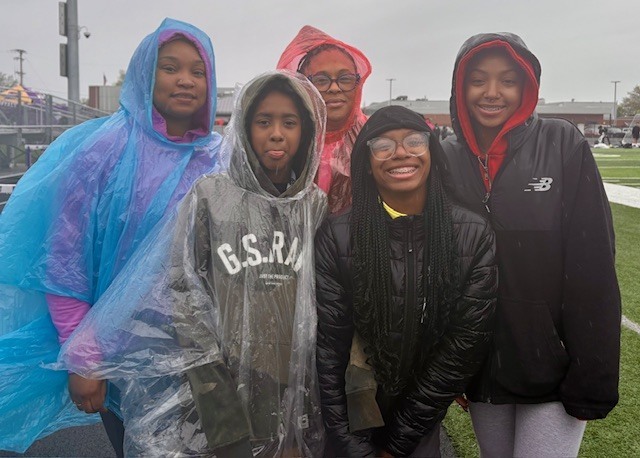 A family standing outside while they wear rain coats. 