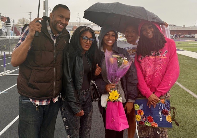 Family standing outside while they hold umbrellas. 