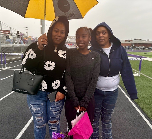 Family standing outside while they hold a umbrella. 