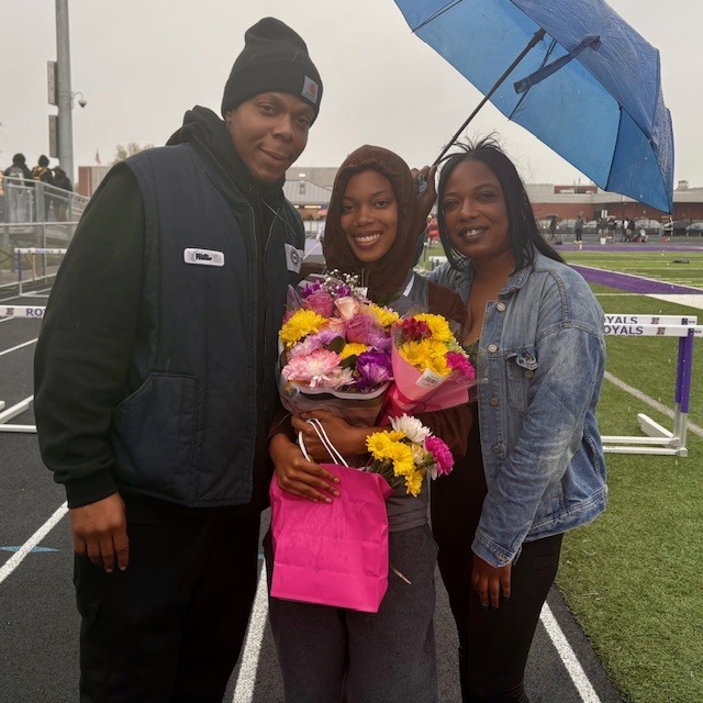 Family standing outside while they hold a umbrella. 