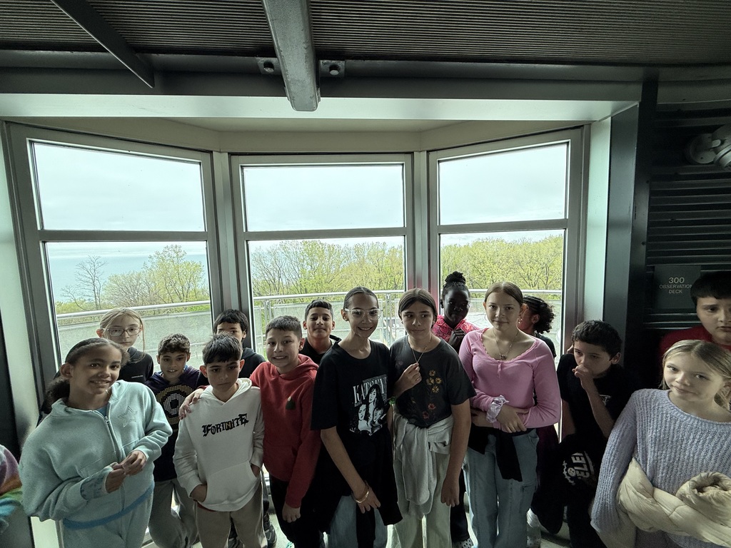 Group of smiling students on observation deck with Lake Erie and trees in the background. 