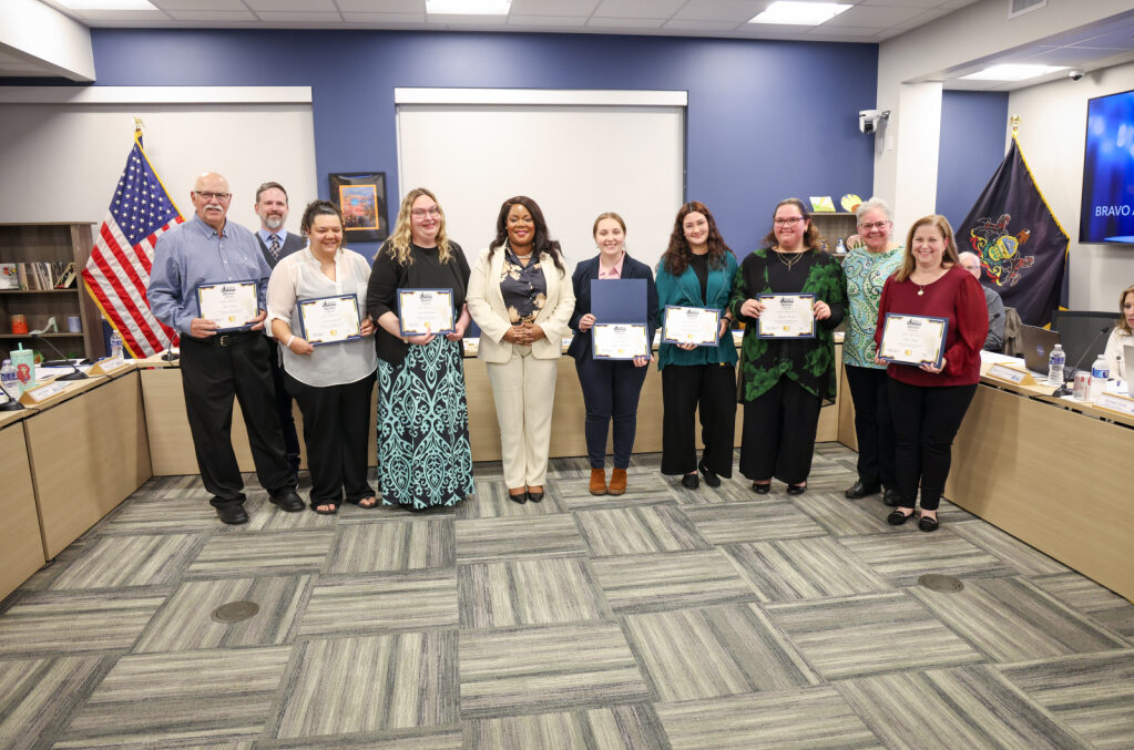 Staff holding their Bravo Awards and standing with Superintendent Dr. Natalyn Gibbs, School board president Dr. Jay Breneman, and Director Linda Graff.