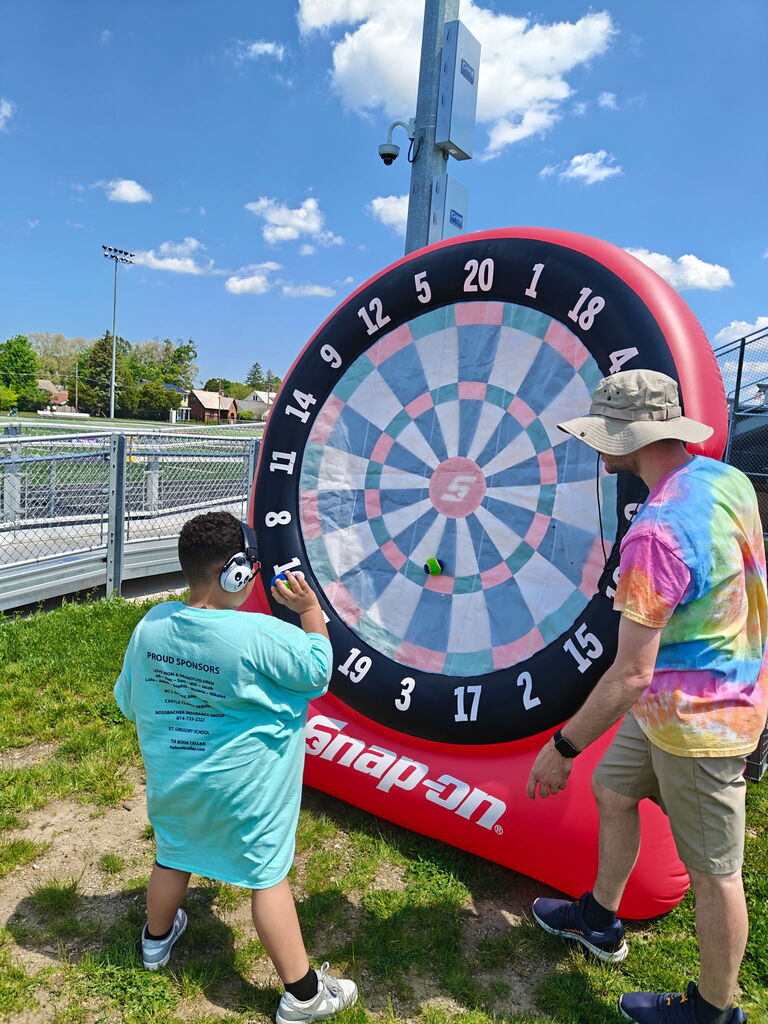 student throwing ball at dartboard for Special Olympics
