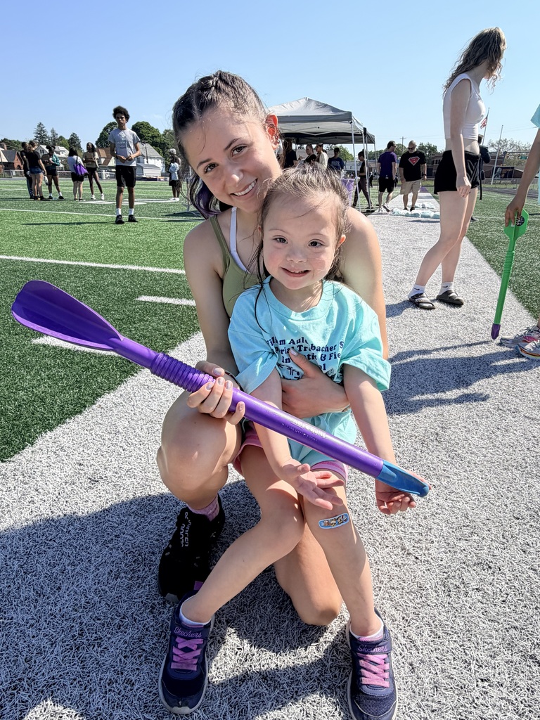 student and special Olympics volunteer with stick.