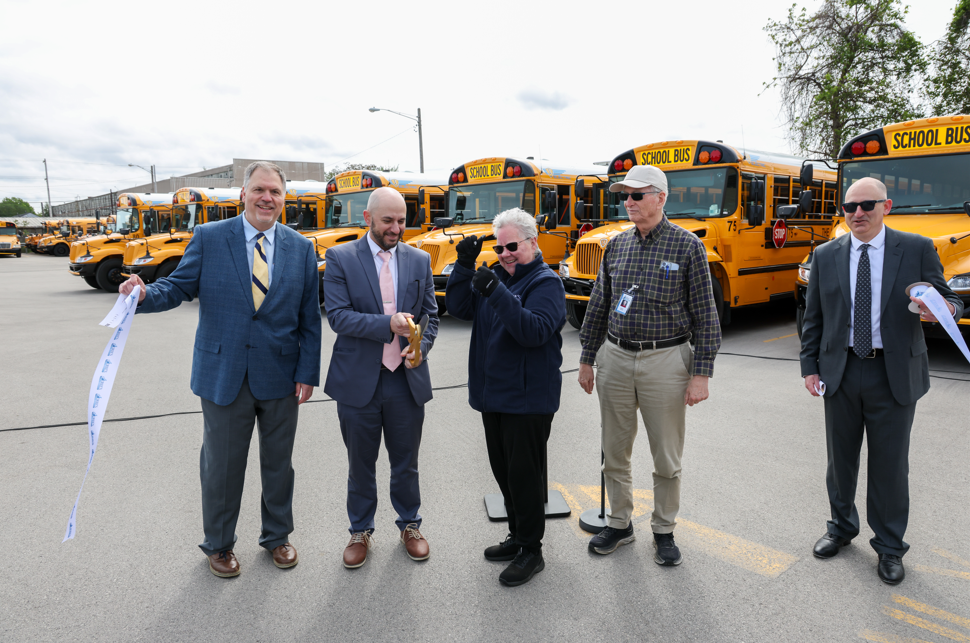 Assistant Superintendent Neal Brokman and Director Linda Graff are cutting the ribbon for the new buses.