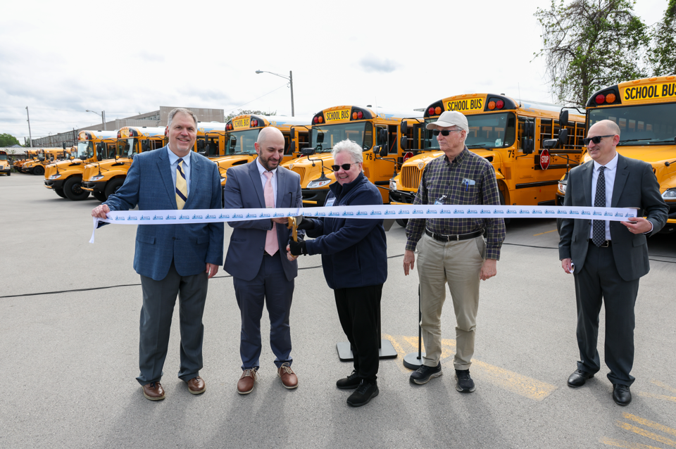 Assistant Superintendent Neal Brokman and Director Linda Graff are cutting the ribbon for the new buses.