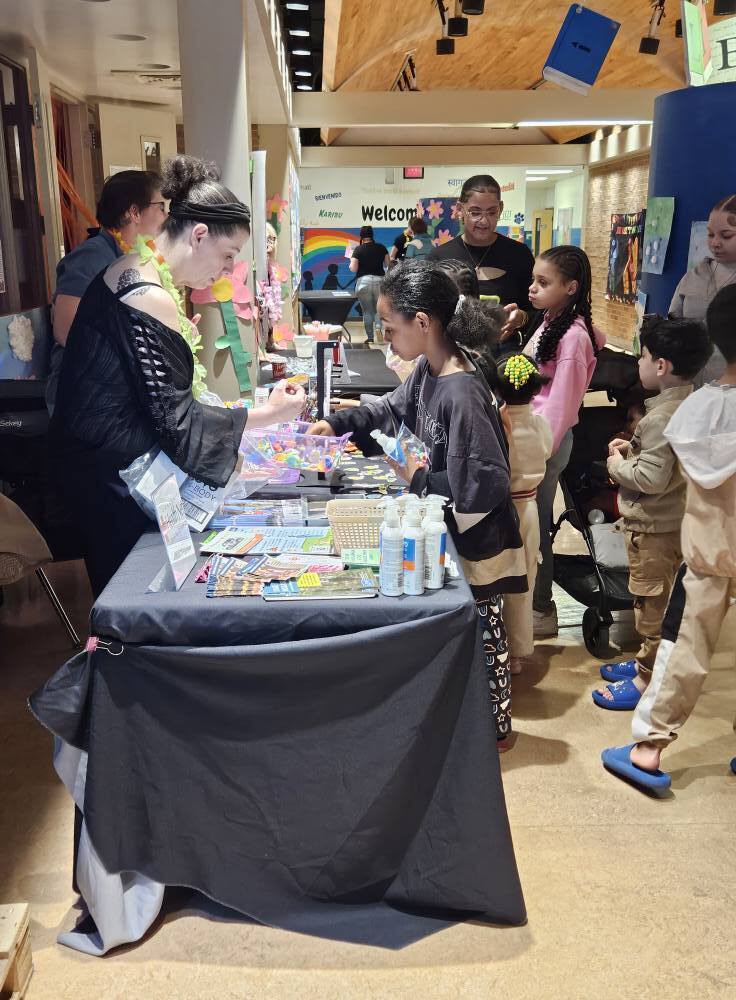 students and families at community booth at summer resource fair
