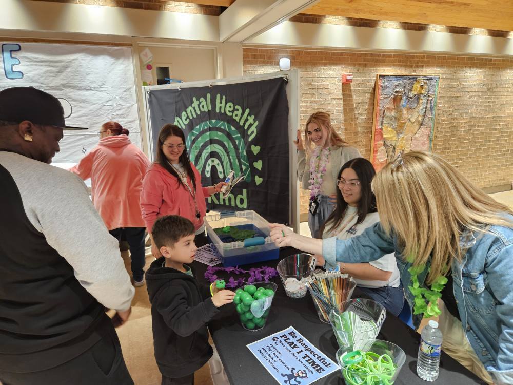 teachers and family at game in Mental Health Awareness station at summer resource fair