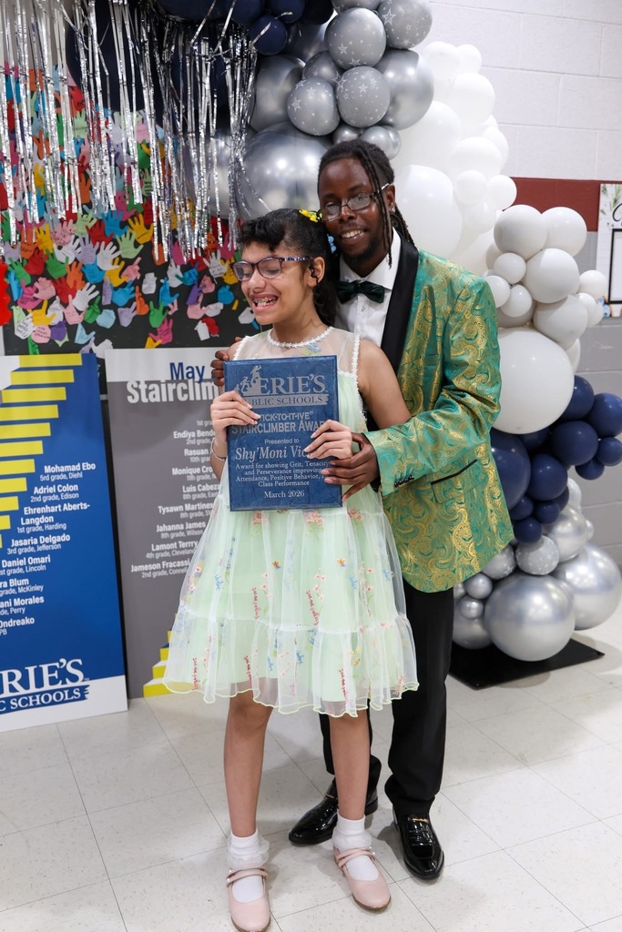 A student posing next to a man while holding her Stairclimber award.