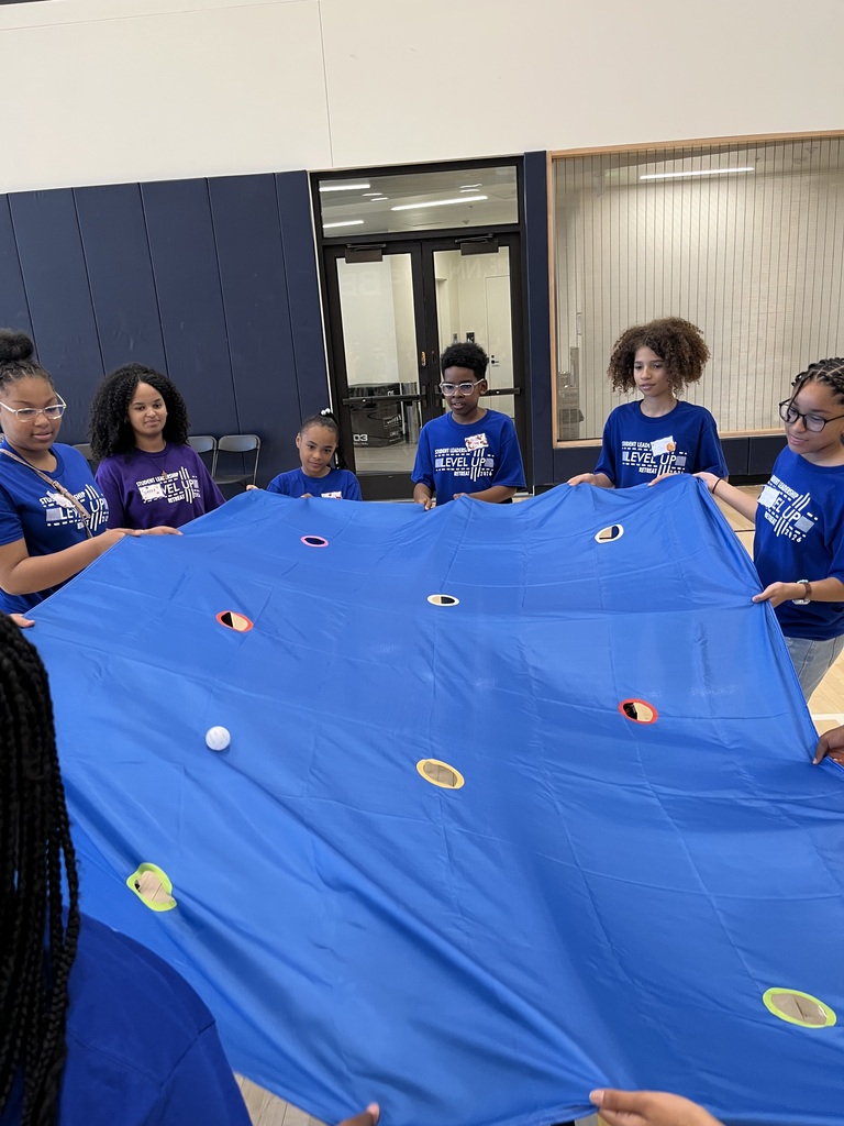 Students participating in the parachute activity trying to get color coded balls into the matching holes.