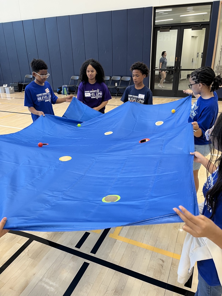 Students participating in the parachute activity trying to get color coded balls into the matching holes.