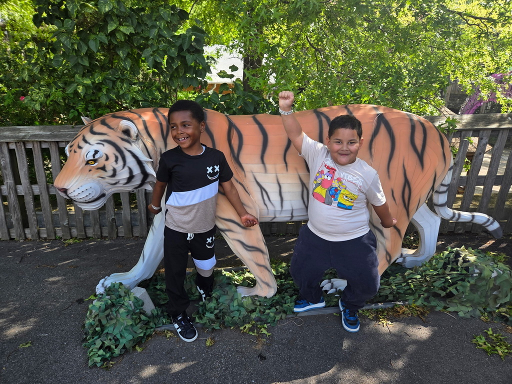 Students posing in front of a fake tiger at the zoo.