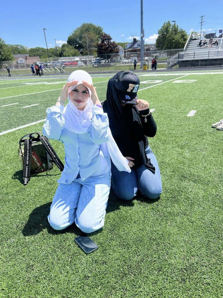 Two students posing on the Erie High football field enjoying the sunshine.