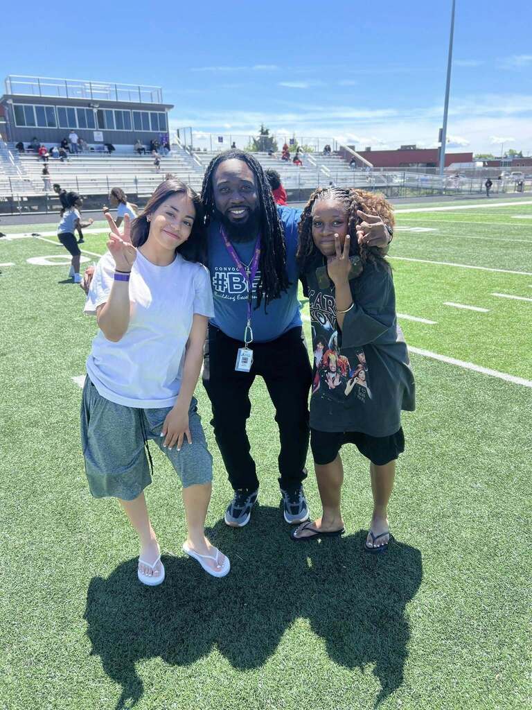 Two Erie High students and Erie High staff posing on Erie High field.