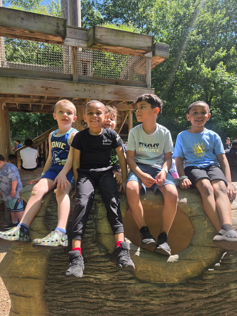 Four boys sitting on a play ship at the zoo.