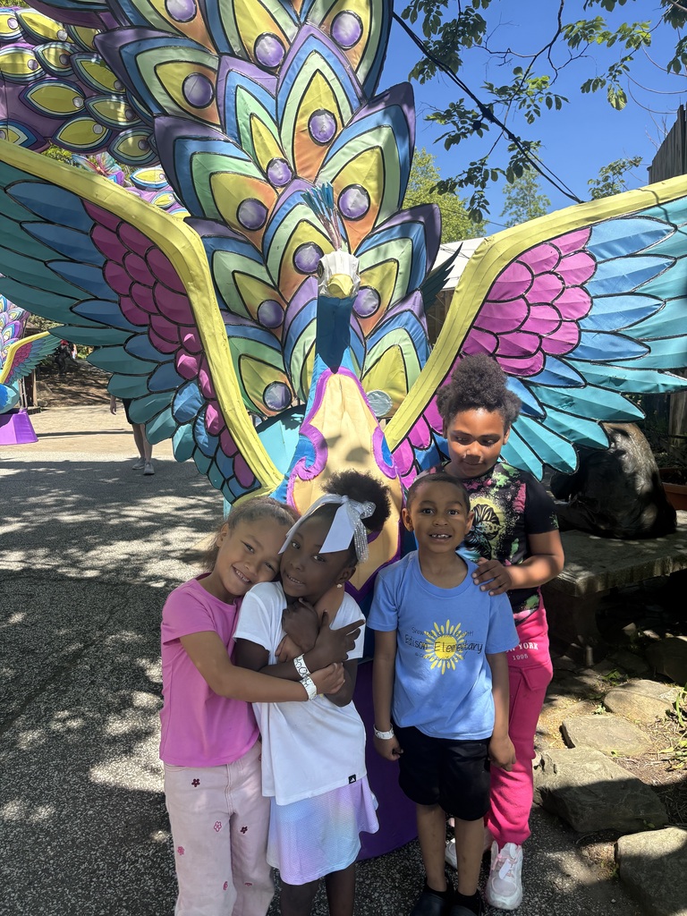 Students posing in front of a colorful statue at the zoo,