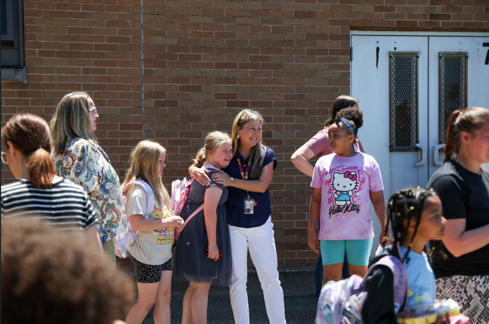A student crying as her teacher hugs her on the last day of school. 