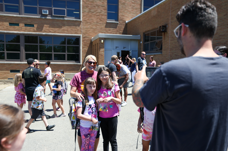Students posing with teacher as a man takes their photo. 