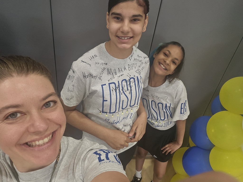 Two students smiling with their teacher for a picture.