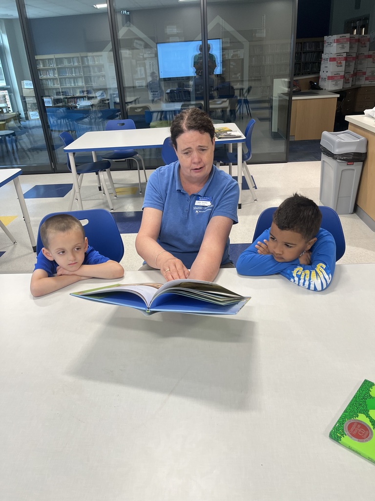 Students reading a book with a volunteer.
