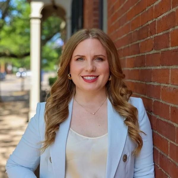 Kristen Weibel standing against a brick wall.