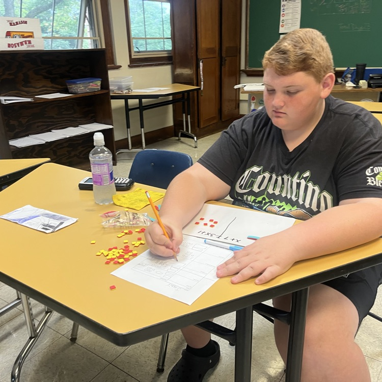 A student sitting at a desk and doing math with tiles.