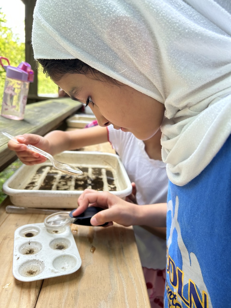 Student looking at a tray with a magnafying glass.