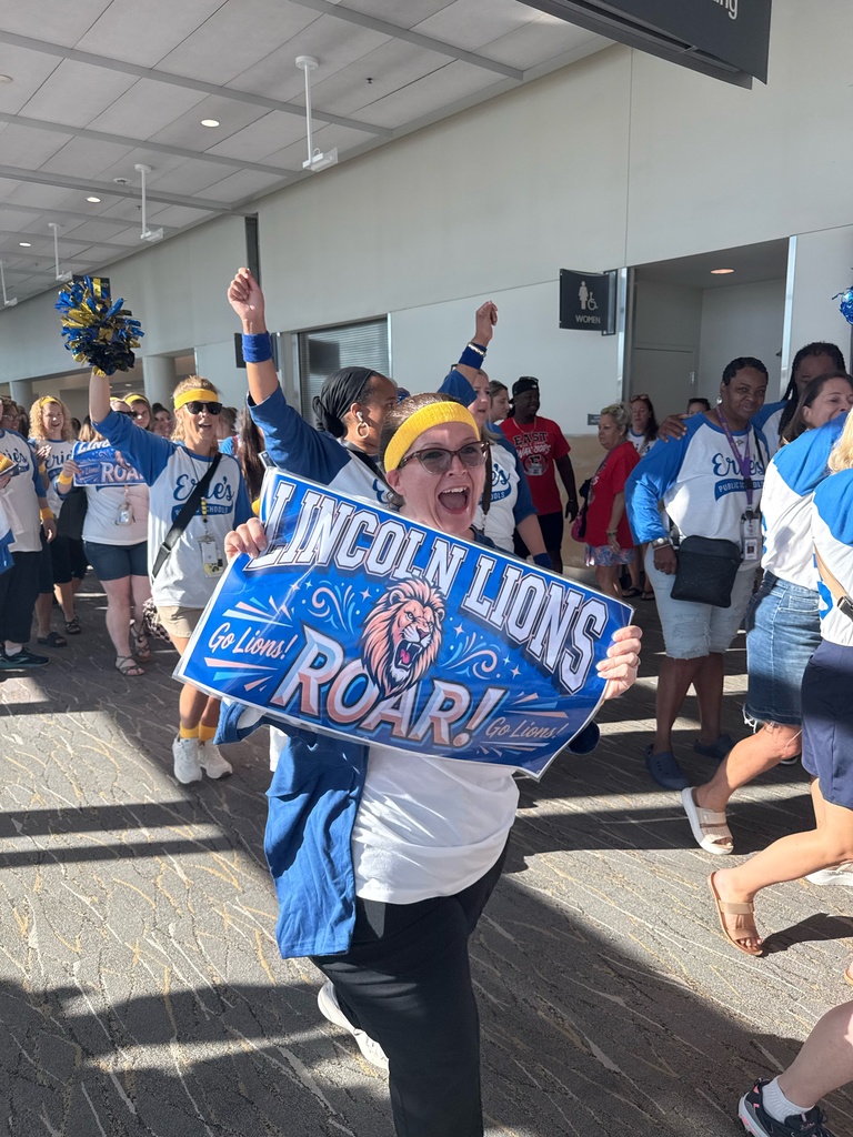 Lincoln staff carrying a sign that says "Lincoln Lions ROAR!"