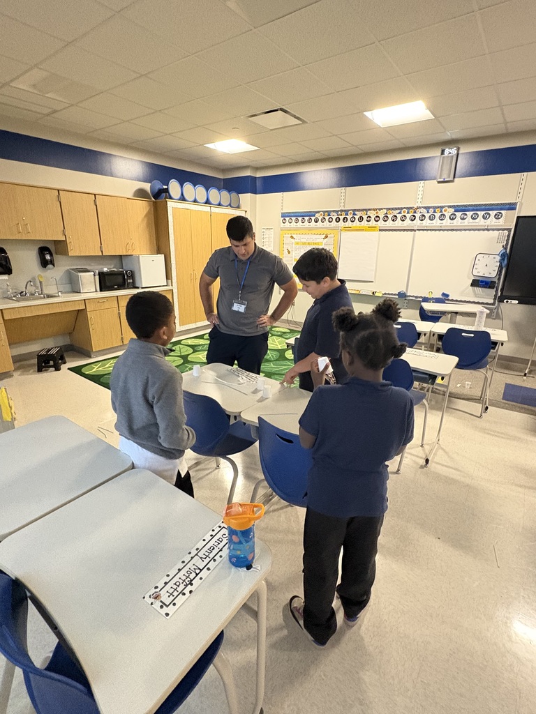 Students standing around a group of desks