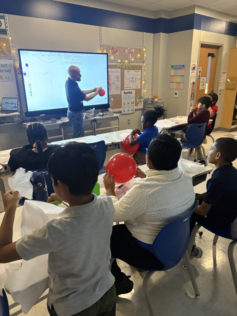 Volunteer holding a balloon, showing students how to do an experiment
