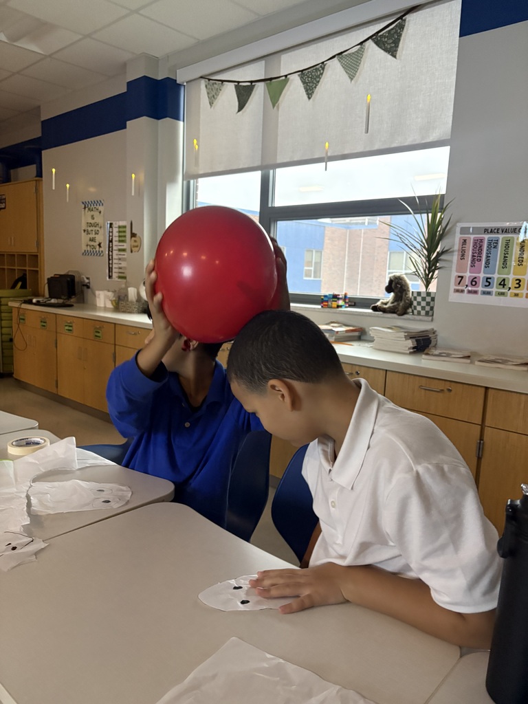 Student rubbing a balloon on another student's head