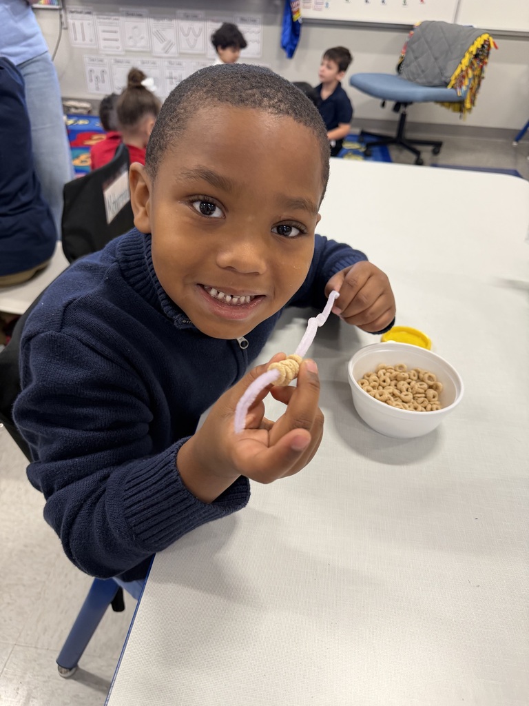 Student stringing cheerios on a pipe cleaner