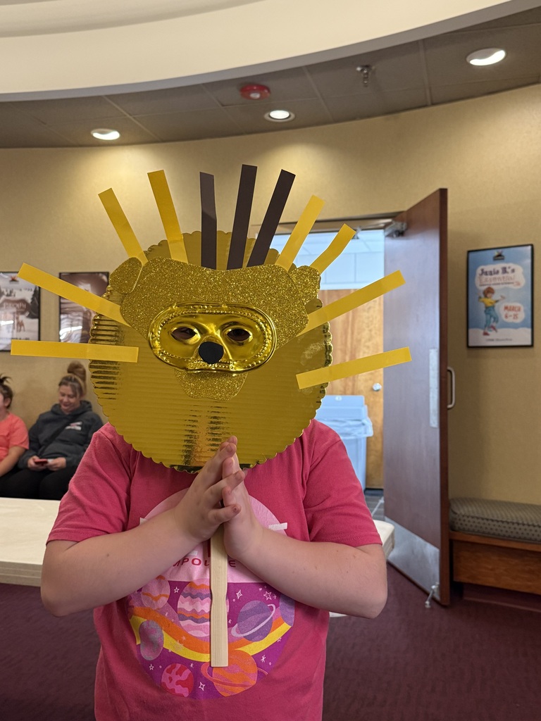 Student holding a mask in front of her face. Mask looks like a lion