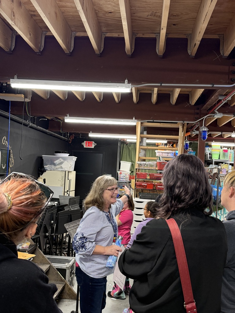 Students and families taking a tour of the storage/prep area under the stage