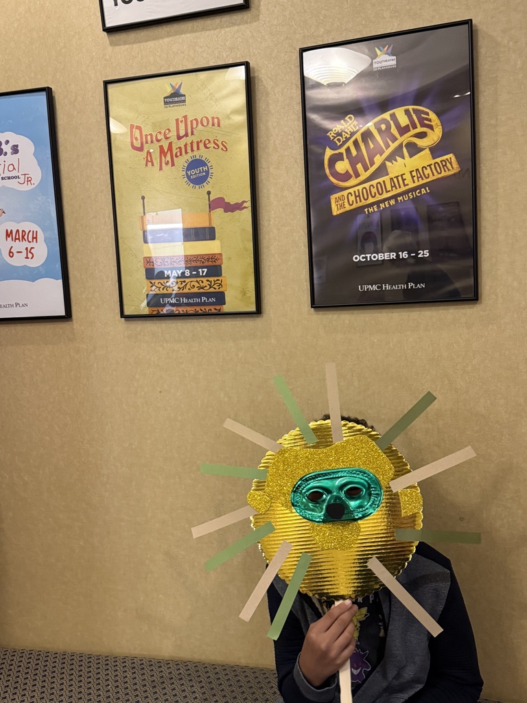 Student with a mask standing in front of signs for upcoming shows