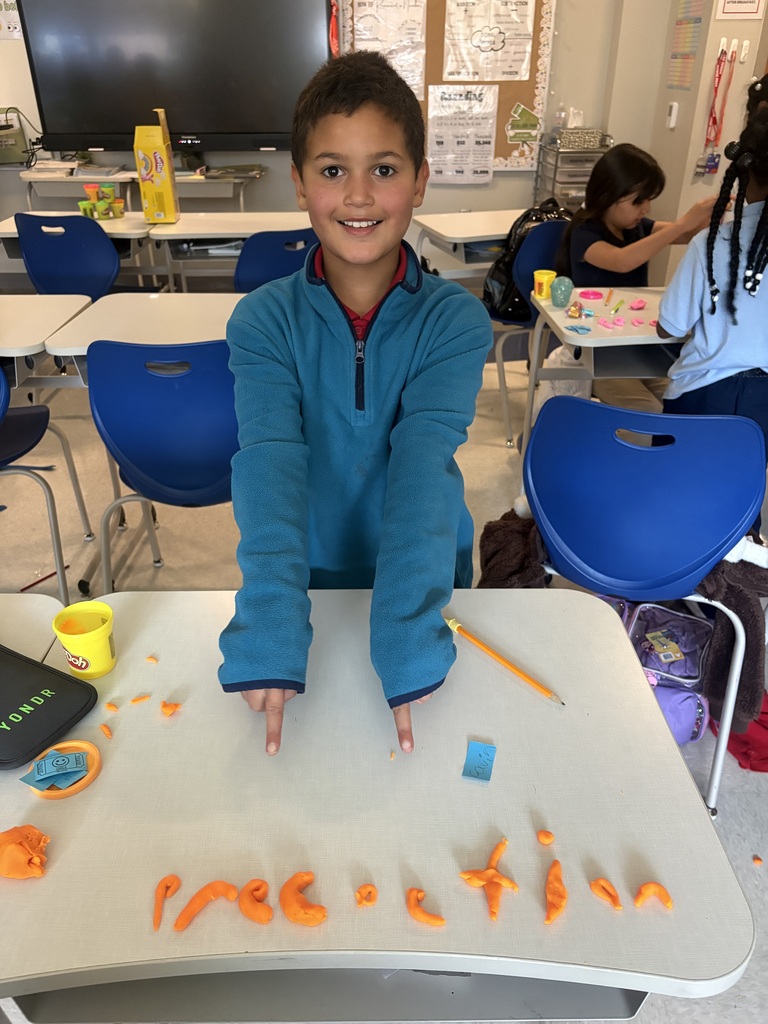 Student pointing to a word he spelled using play-doh.