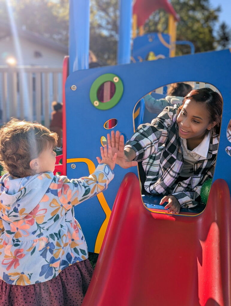 Erie High student Maria high fiving a student from the daycare.