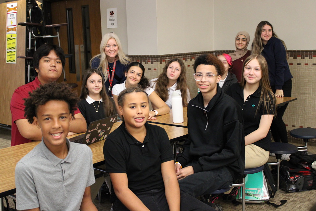 group of students at a cafeteria table with teacher