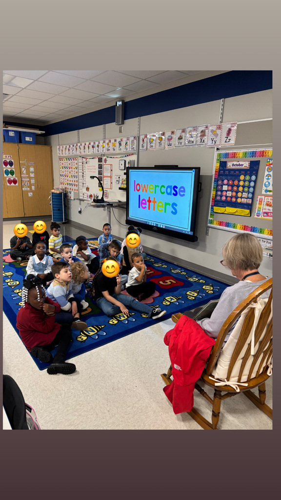 Students sitting on the floor listening to a guest reader.