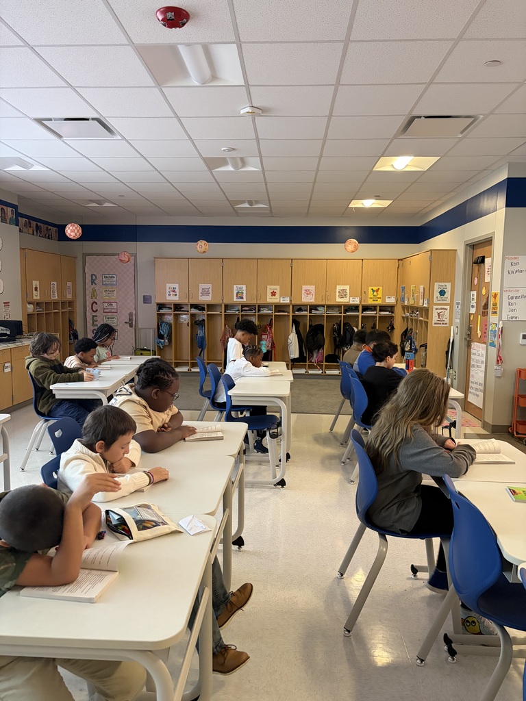 Students sitting at their desks looking through books.
