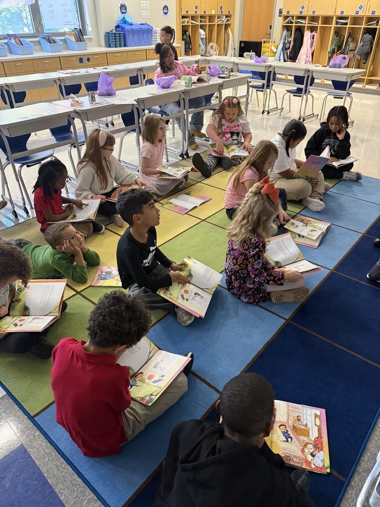 Students sitting on the floor looking through books.