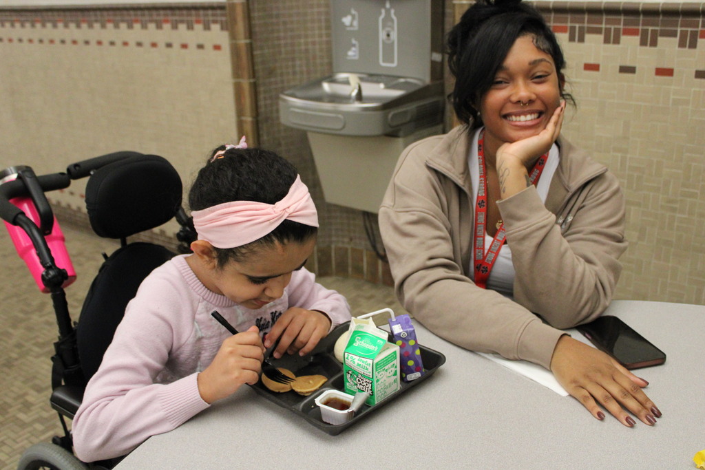 student and adult at a table with breakfast