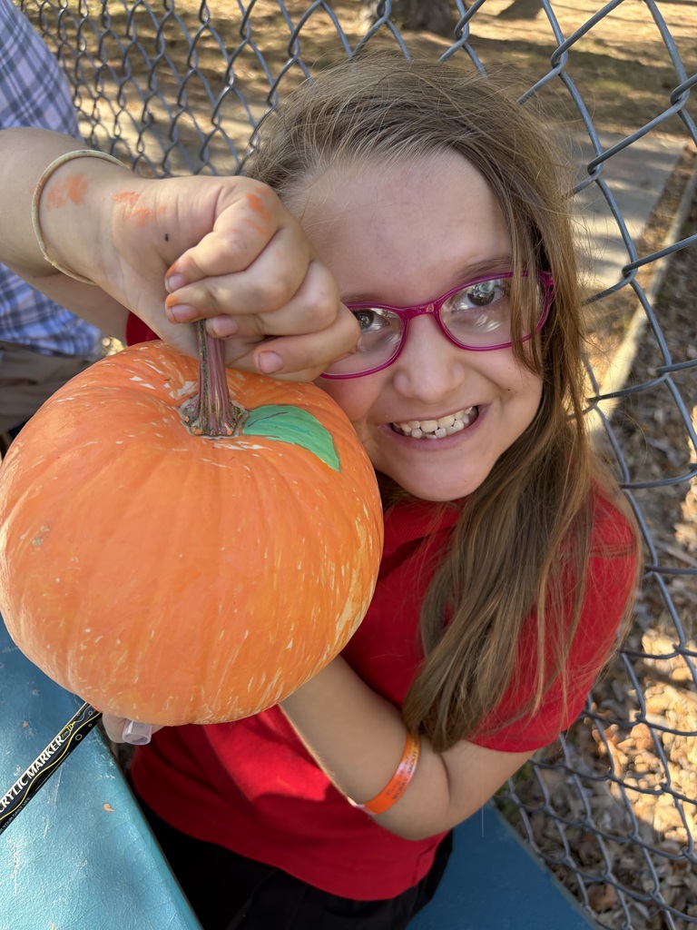 Student smiling with their painted pumpkin.